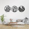 A set of three black metal line art floral wreaths displayed on a white wall above a light gray sofa.