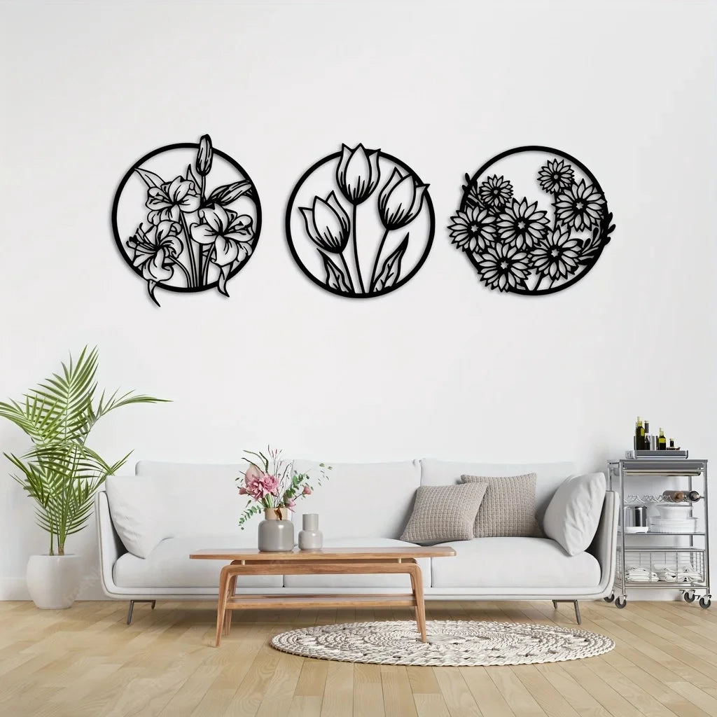 A set of three black metal line art floral wreaths displayed on a white wall above a light gray sofa.