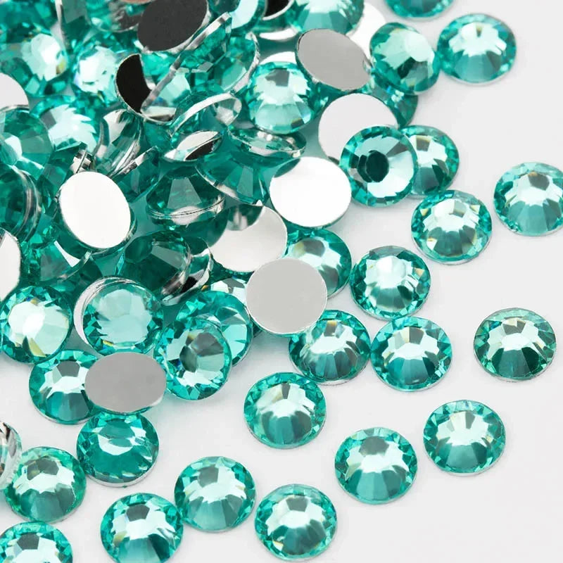 A close-up view of various round flatback resin rhinestones in shades of teal and aqua.