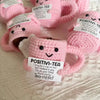 Pink crocheted tea cup ornament with a motivational charm featuring the text POSITIVI-TEA