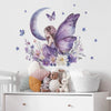 A watercolor illustration of a girl with butterfly wings sitting on a crescent moon surrounded by flowers and stars