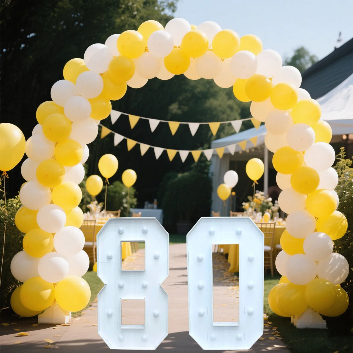 A large archway made of yellow and white balloons frames a light-up marquee number sign displaying 80.