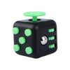A black fidget cube with light green dots and a green top, used as a stress relief toy.