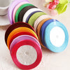 A collection of colorful satin ribbon spools arranged in a fan shape on a light surface.