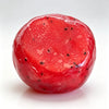 A bright red, translucent watermelon-shaped squishy fidget toy with black seeds.