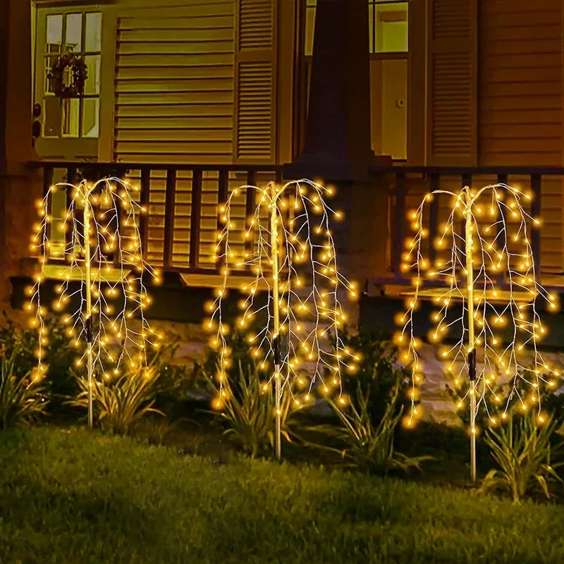 A row of solar garden lights with a starburst effect illuminating grass and plants in the evening.