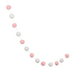 A string of colorful felt balls in various shades of pink and white used for home decor.