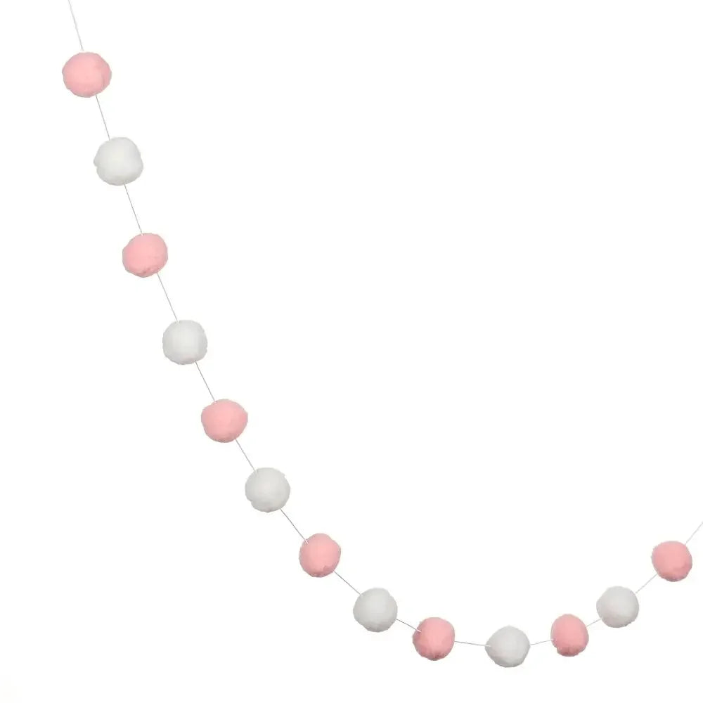 A string of colorful felt balls in various shades of pink and white used for home decor.