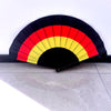 A black and red striped folding fan shaped like a country flag, displayed on a gray floor.