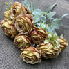 A bouquet of nine realistic silk roses in shades of golden yellow and soft beige with light green foliage.