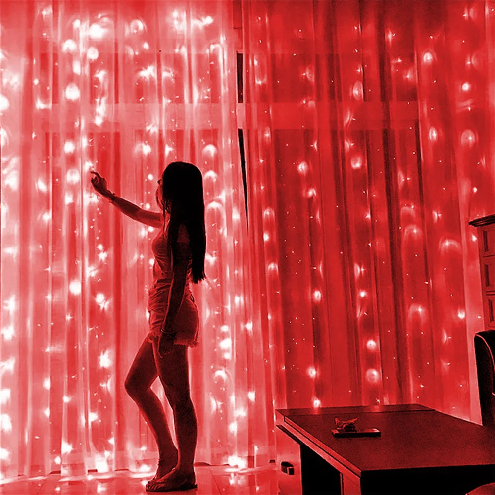 A woman stands in front of a bright red curtain decorated with glowing fairy lights.
