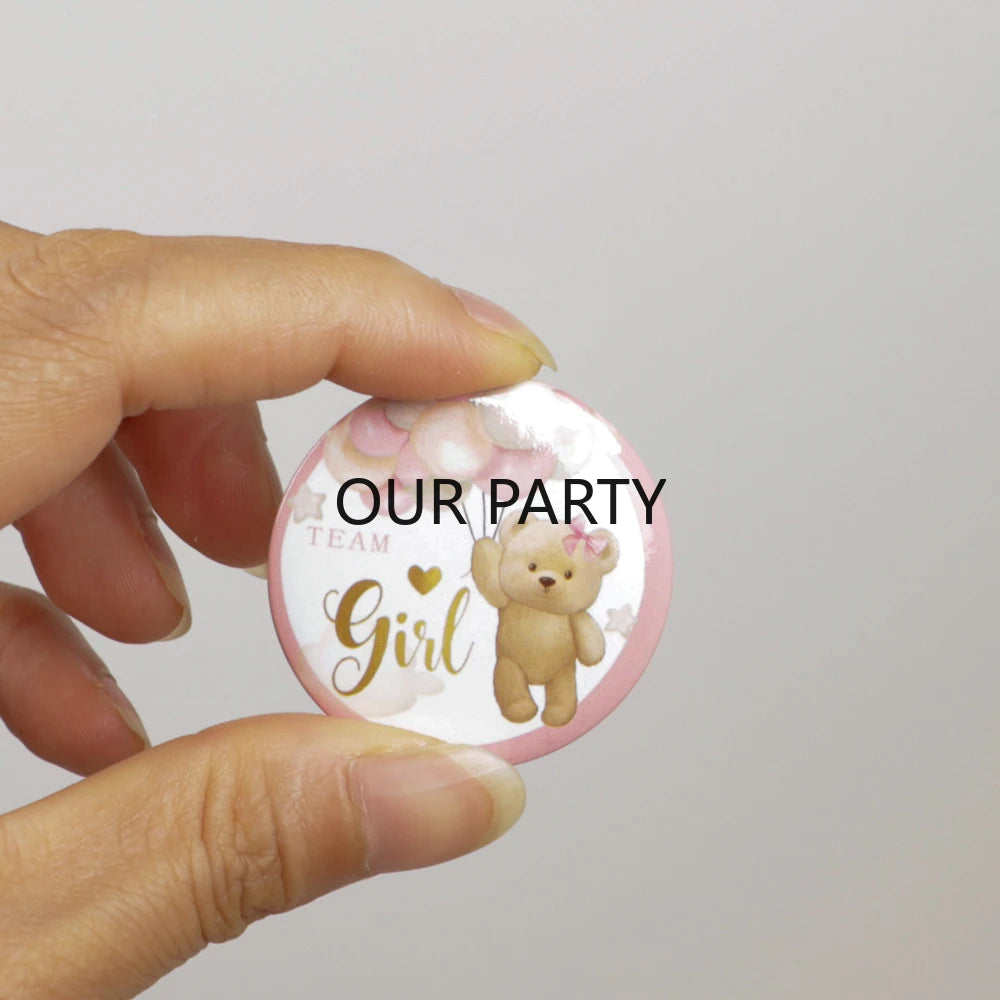A hand holds a round pink pin badge featuring a cartoon bear and the text Our Party Team Girl