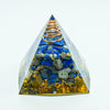 A clear pyramid crystal structure filled with blue and gray stones and a coiled gold wire.