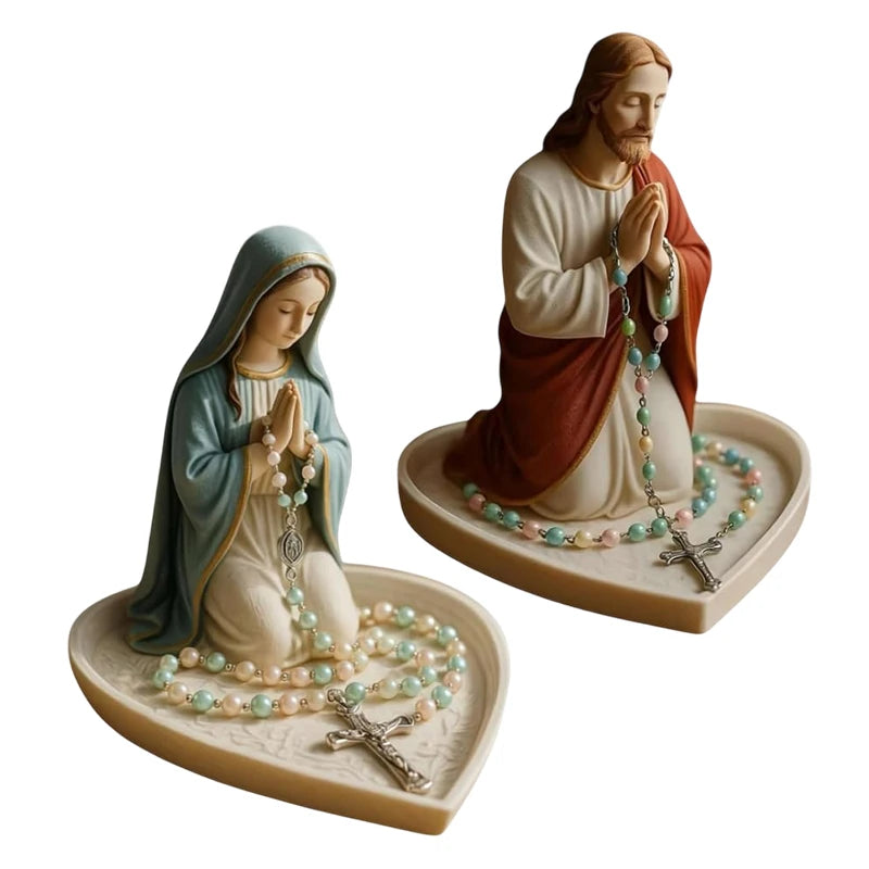 A statue of Jesus and the Virgin Mary with rosaries displayed on a tray.