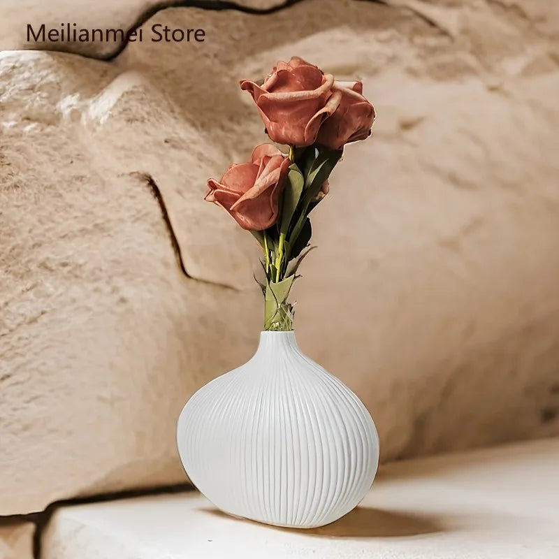 A single pink rose in a white textured vase displayed against a neutral background.
