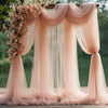 Pink sheer tulle fabric draped as a wedding or event backdrop