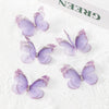 Several purple and lilac embroidered butterfly patches are displayed on white fabric.