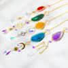 A collection of natural agate sun catcher crystals strung on gold wire, featuring various colors like red, green, yellow, blu