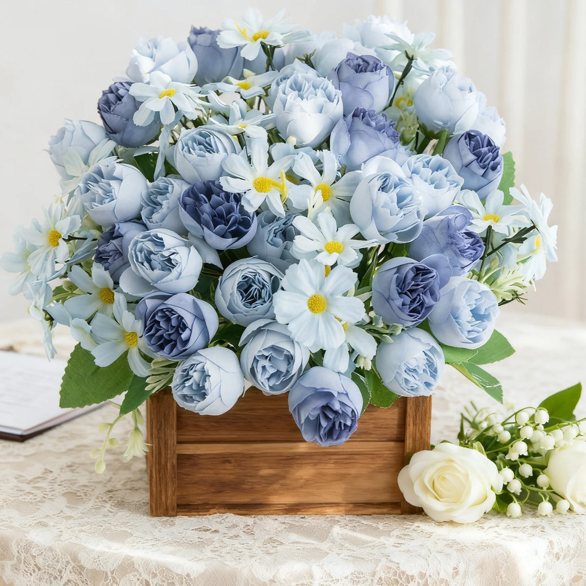 Un ramo de rosas de seda artificial en tonos azules y lavanda, arreglado en una caja de madera.