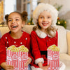Two smiling girls in red festive outfits holding popcorn buckets