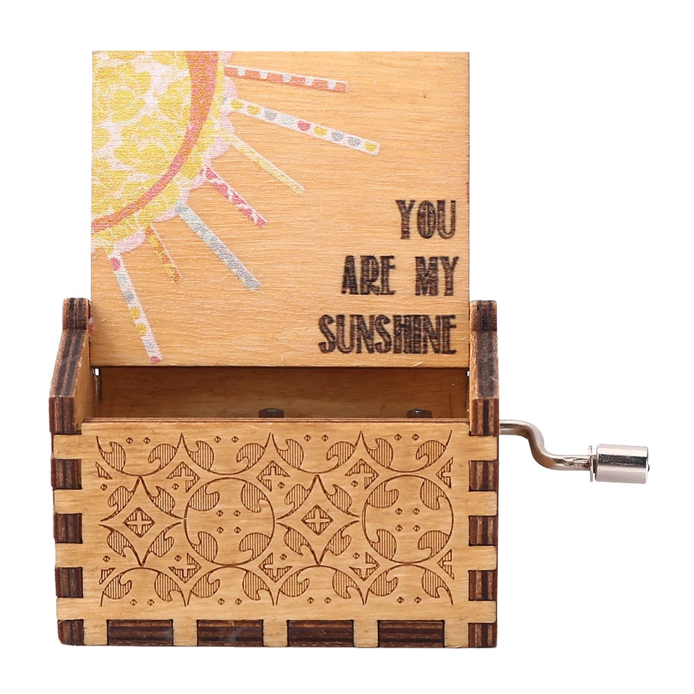A vintage hand crank music box with a light wood box featuring a sun design and decorative carving.