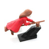 A figurine of a witch with long hair in a red dress is positioned on a black dashboard drift decor.