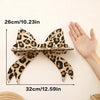 A leopard print bow-shaped wall mounted storage rack shown next to a hand for scale.