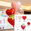 A set of strawberry theme birthday decorations including a banner, heart-shaped balloons, and honeycomb ornaments.