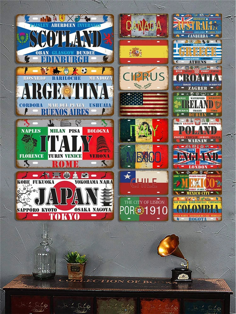 A collection of vintage metal tin signs featuring various countries and cities mounted on a gray wall.