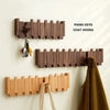 Wooden piano keys coat hooks mounted on a white wall above a brown coat hanger.