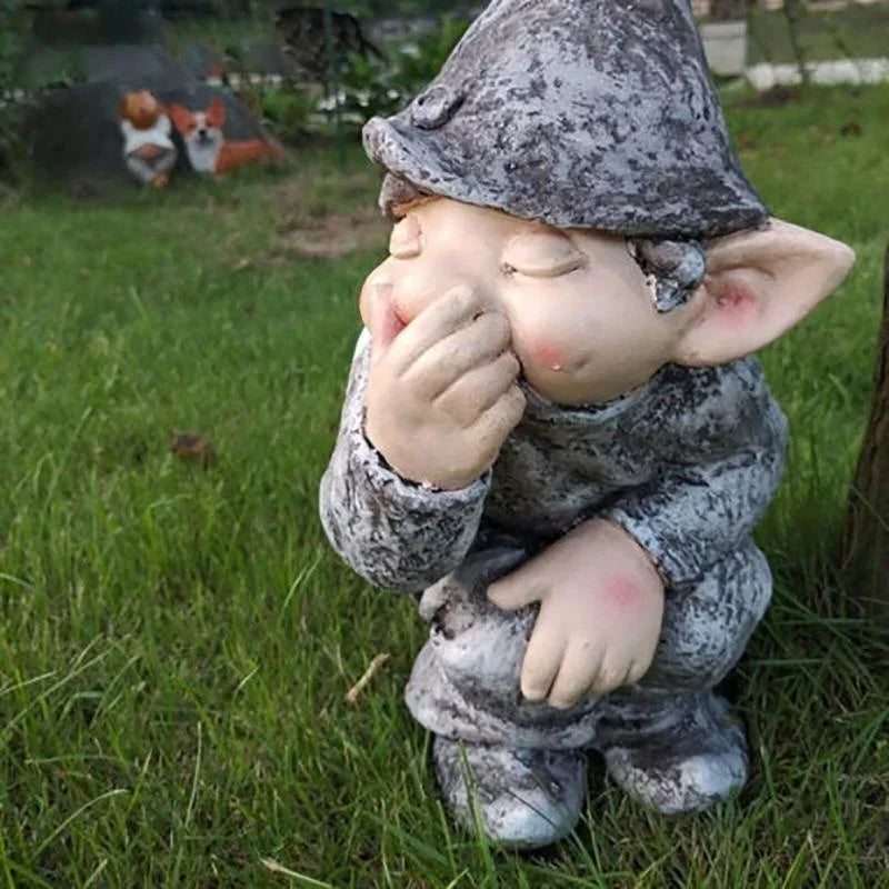 A ceramic statue of a gnome with closed eyes and a hand covering his mouth sitting in green grass.