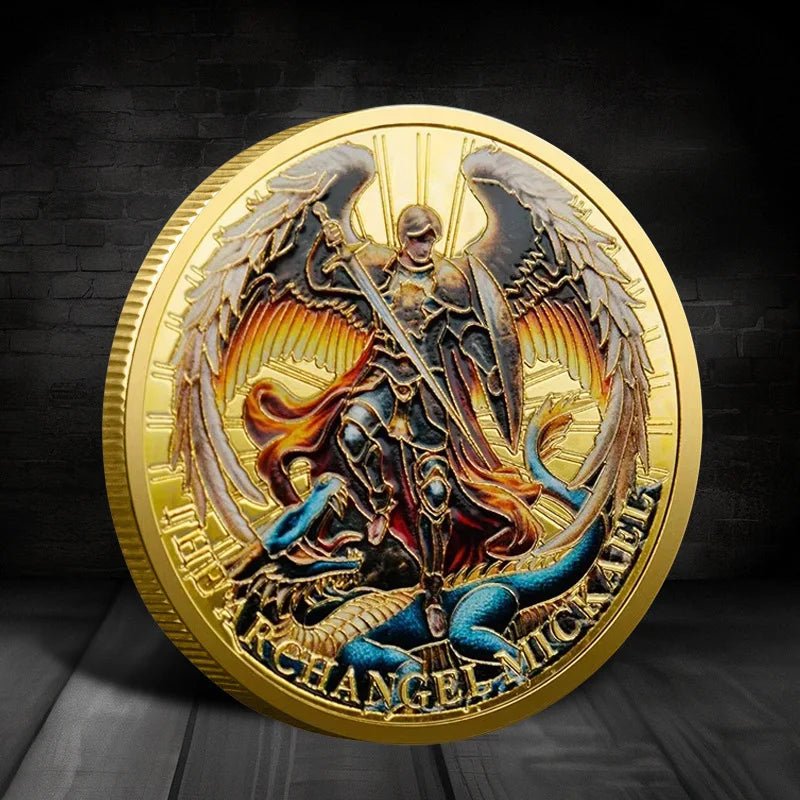 A gold-plated collectible coin featuring an Archangel Michael with large feathered wings.