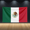 A large Mexican flag tapestry displayed on a dark wall with spotlights.