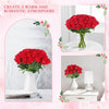 A bouquet of vibrant red artificial silk roses in a white pitcher displayed on a table.