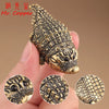 Close-up of an antique brass crocodile figurine with intricate texture, held in a hand.