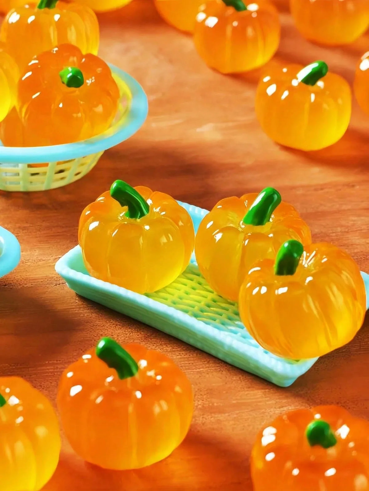 Bright orange mini artificial pumpkins are displayed on a wooden surface and in a light blue basket.
