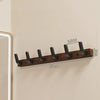 A walnut wood coat rack with eight hooks and a storage shelf mounted on a light-colored wall.