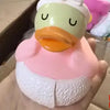 A cute rubber duck bath toy with a yellow beak and pink body is held in a hand.