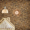 A wall decorated with leopard print wallpaper featuring a wooden house structure and a round clock light fixture.