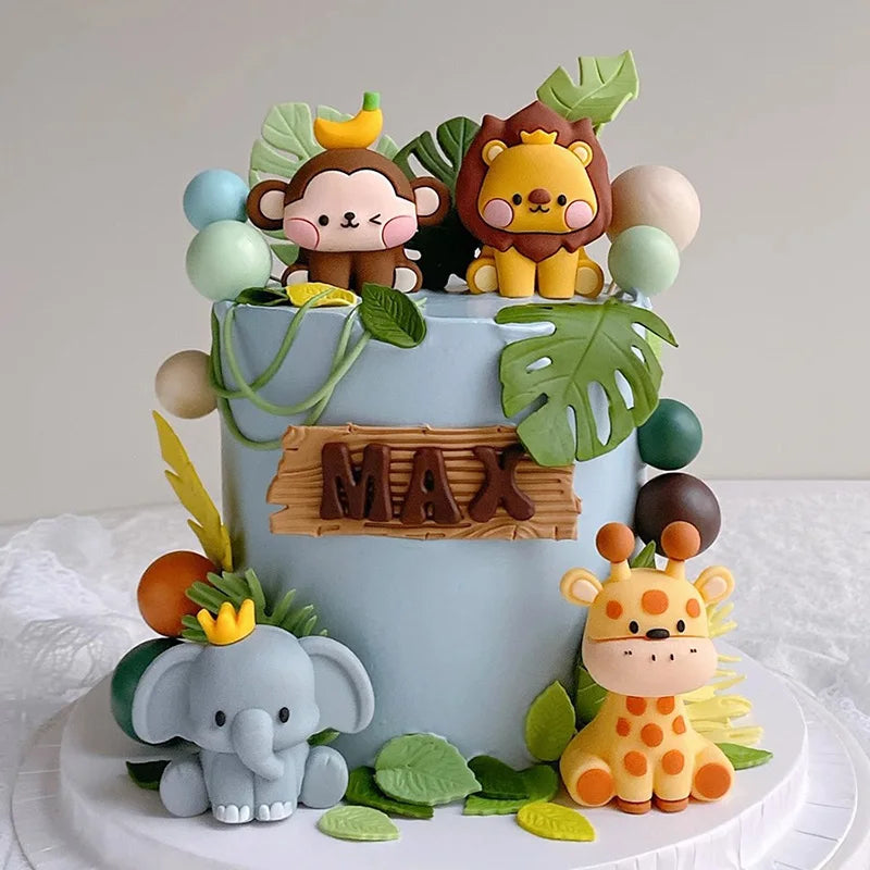 A tiered cake decorated with jungle animal toppers including a lion, monkey, elephant, and giraffe.