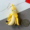 A yellow banana shaped fridge magnet with a smiling face and black accents, placed on a gray surface.