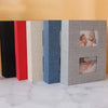 A row of five linen-cover photo albums in black, red, beige, blue, and gray.