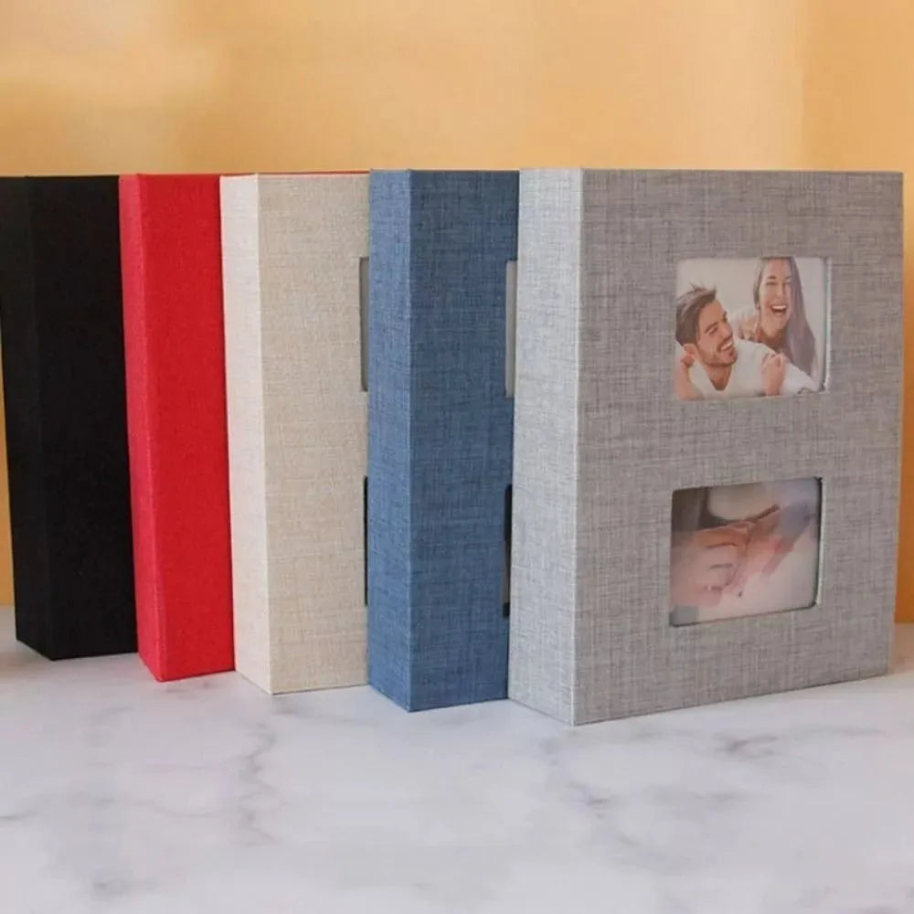 A row of five linen-cover photo albums in black, red, beige, blue, and gray.