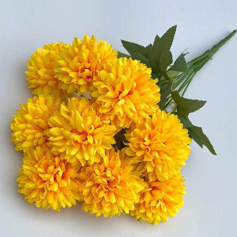A bouquet of artificial yellow flowers, including hydrangea and camellia blooms, with green leaves.