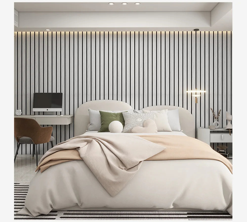 A bedroom featuring a bed with beige linens against a wall of vertical wooden slats and modern lighting.