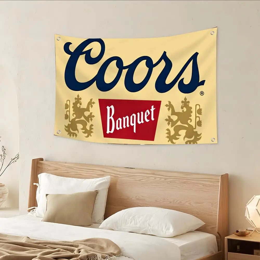 Gelbes Banner mit der Aufschrift Coors in Dunkelblau und einem roten Rechteck mit 'Banquet', über einem Holzbett dargestellt.