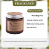 A jar of White Jasmine Mint floral fragrance candle with a silver lid and a label detailing the scent notes.