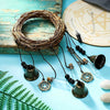 A vintage wicker wreath of thin branches with hanging brass and glass bells on dark cords.