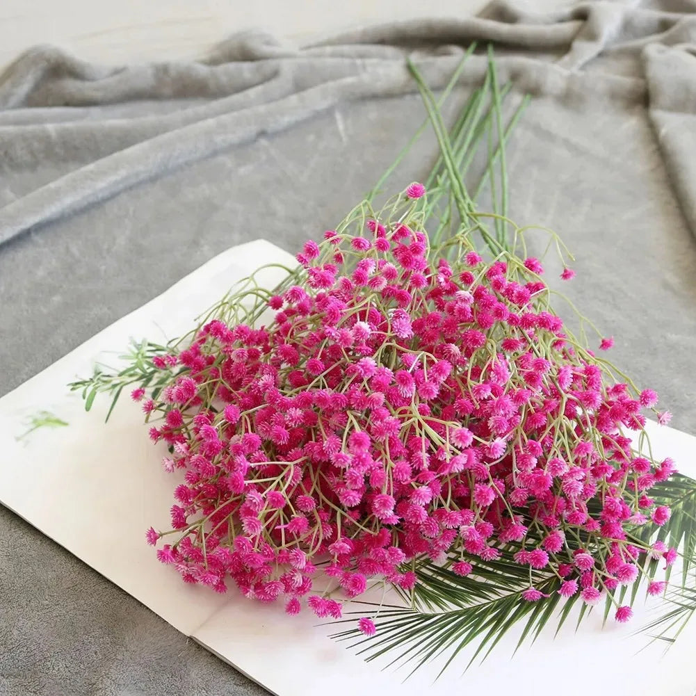 A bouquet of vibrant pink artificial gypsophila flowers arranged on a white rectangular plate.