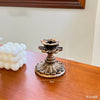 A vintage resin wall sconce candle holder with a fluted design sits on a wooden surface next to white decorative balls.